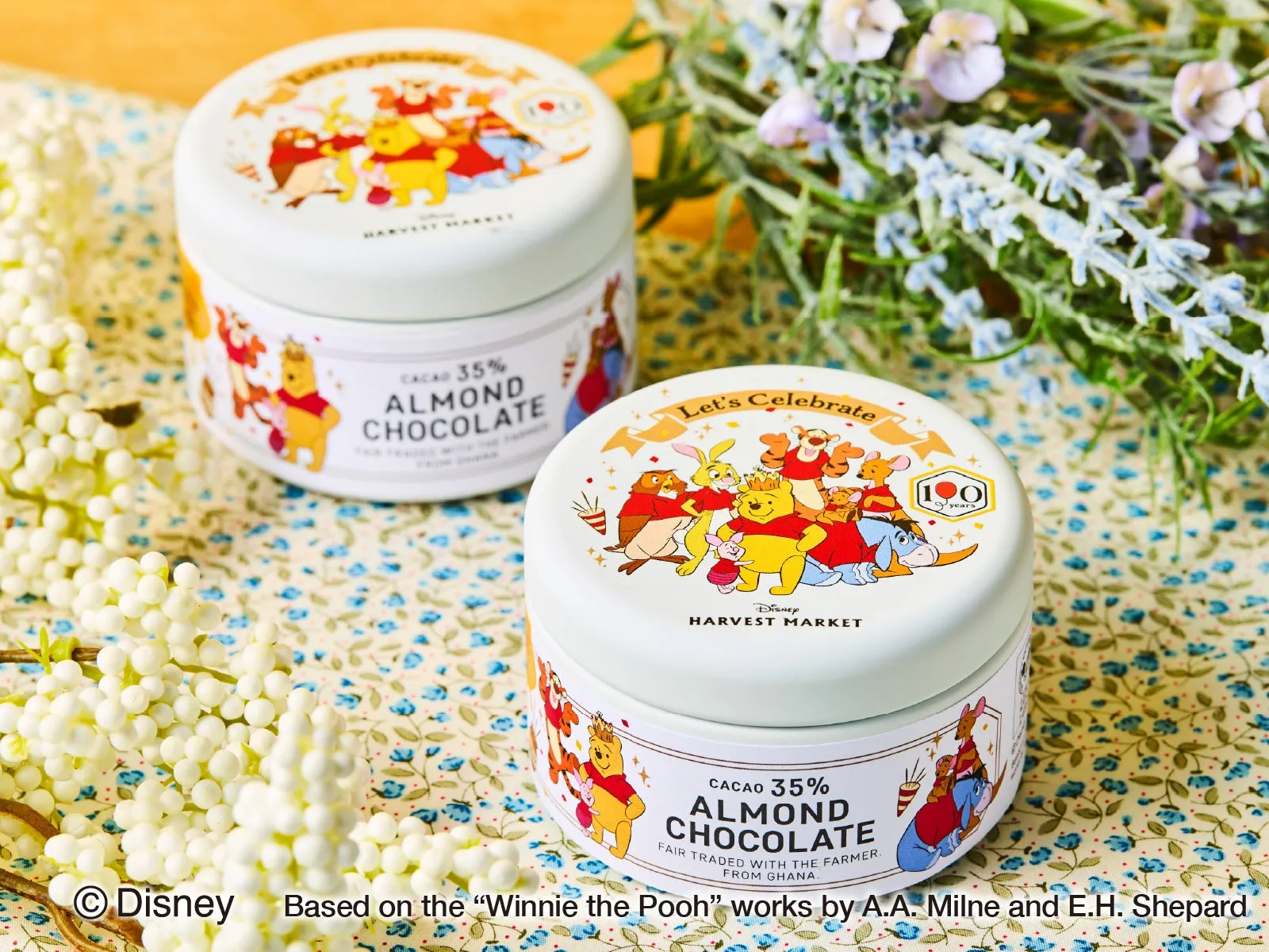 2つの丸い缶に入ったアーモンドチョコレートの画像です。どちらの缶にも、くまのプーさんや仲間たちが描かれており、明るく楽しげな雰囲気です。