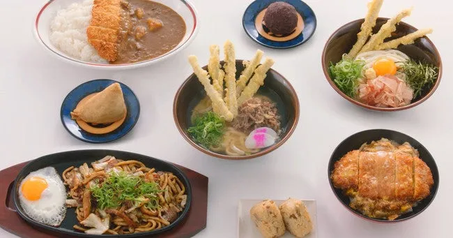 様々な日本食がテーブルに並べられた写真です。カレーライス、揚げ物、うどん、焼きそば、おはぎなど、様々な料理が美味しそうに並んでいます。