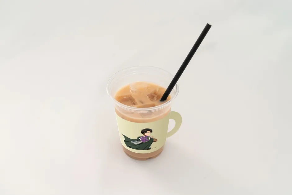 透明なプラスチックカップに入ったアイスコーヒー。カップにはキャラクターのイラストが描かれたスリーブが巻かれており、黒いストローが刺さっている。