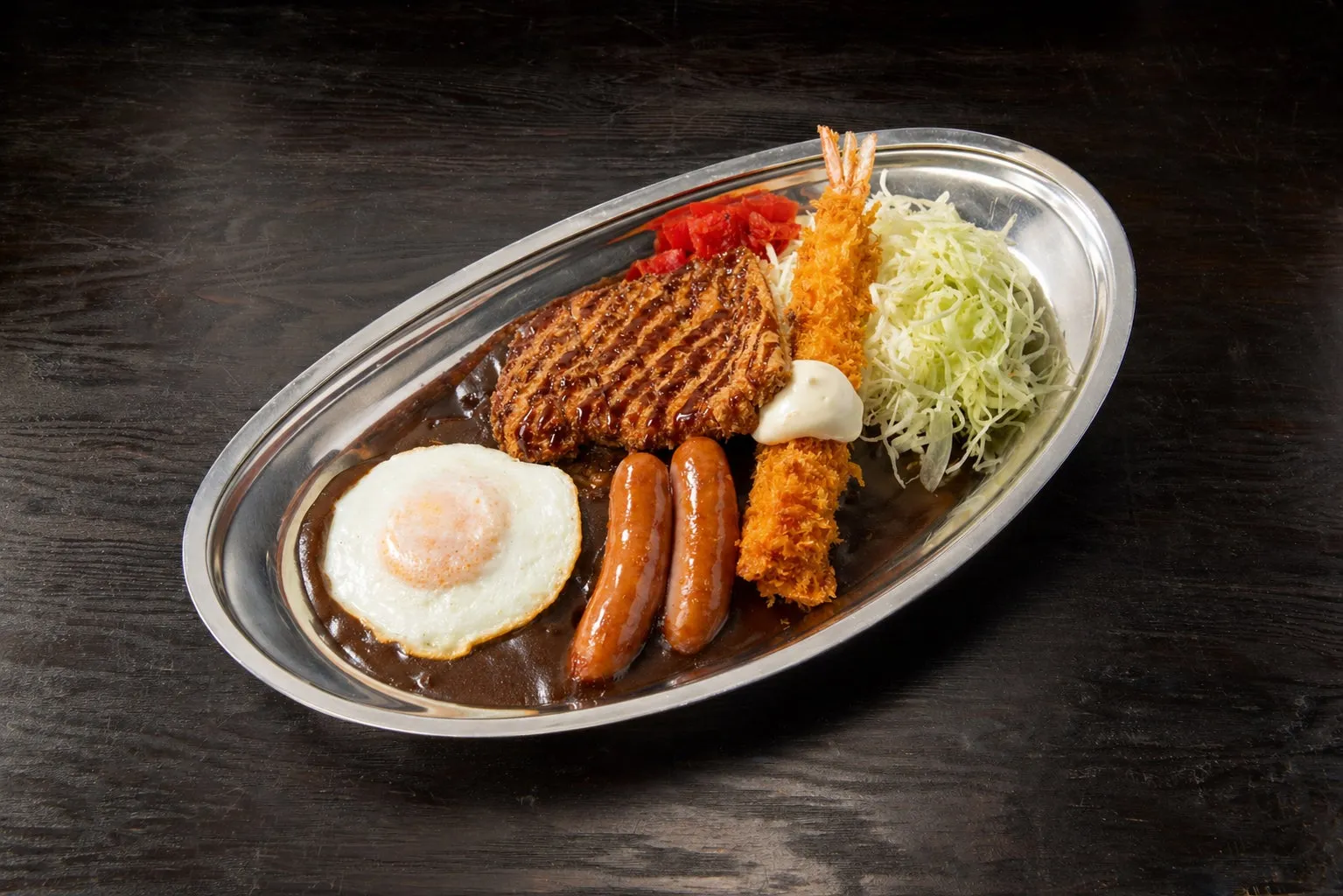 揚げ物や卵、ソーセージなどがカレーの上に乗った料理の写真です。