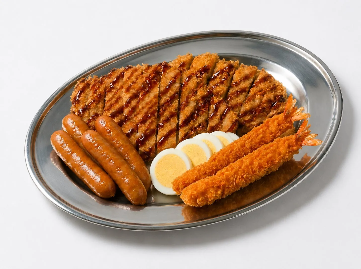 銀色の皿に盛られた、揚げ物やソーセージ、ゆで卵など、様々な種類の料理が写っています。とんかつ、エビフライ、ソーセージ、ゆで卵が写っています。