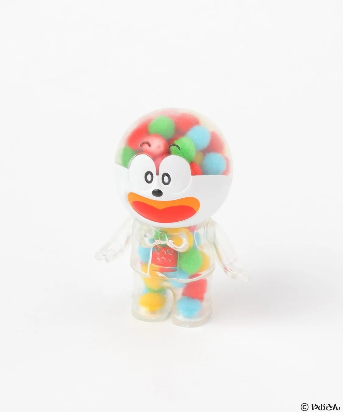 透明なプラスチック製のキャラクターのおもちゃ。頭の部分は丸く、中にカラフルなボールが入っている。口や目、蝶ネクタイのような装飾があり、全体的に可愛らしいデザイン。