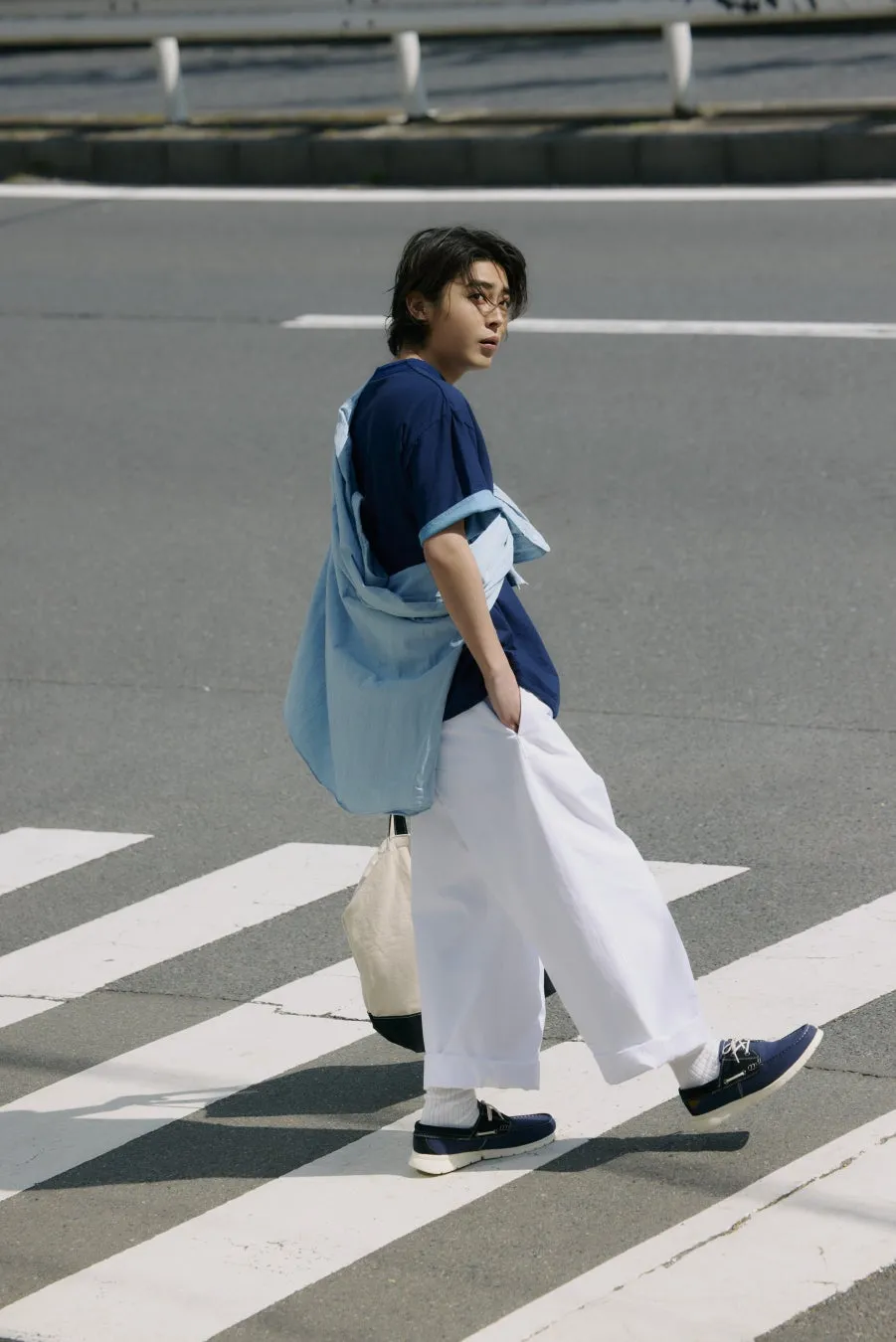 横断歩道を歩く男性のファッションスナップ。紺色の靴を履いている。
