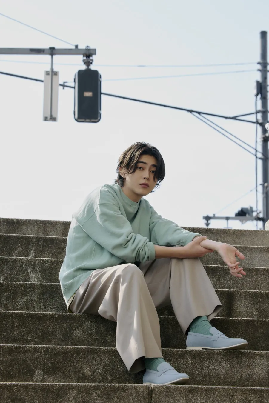 階段に座ってポーズをとる男性のファッションポートレート。