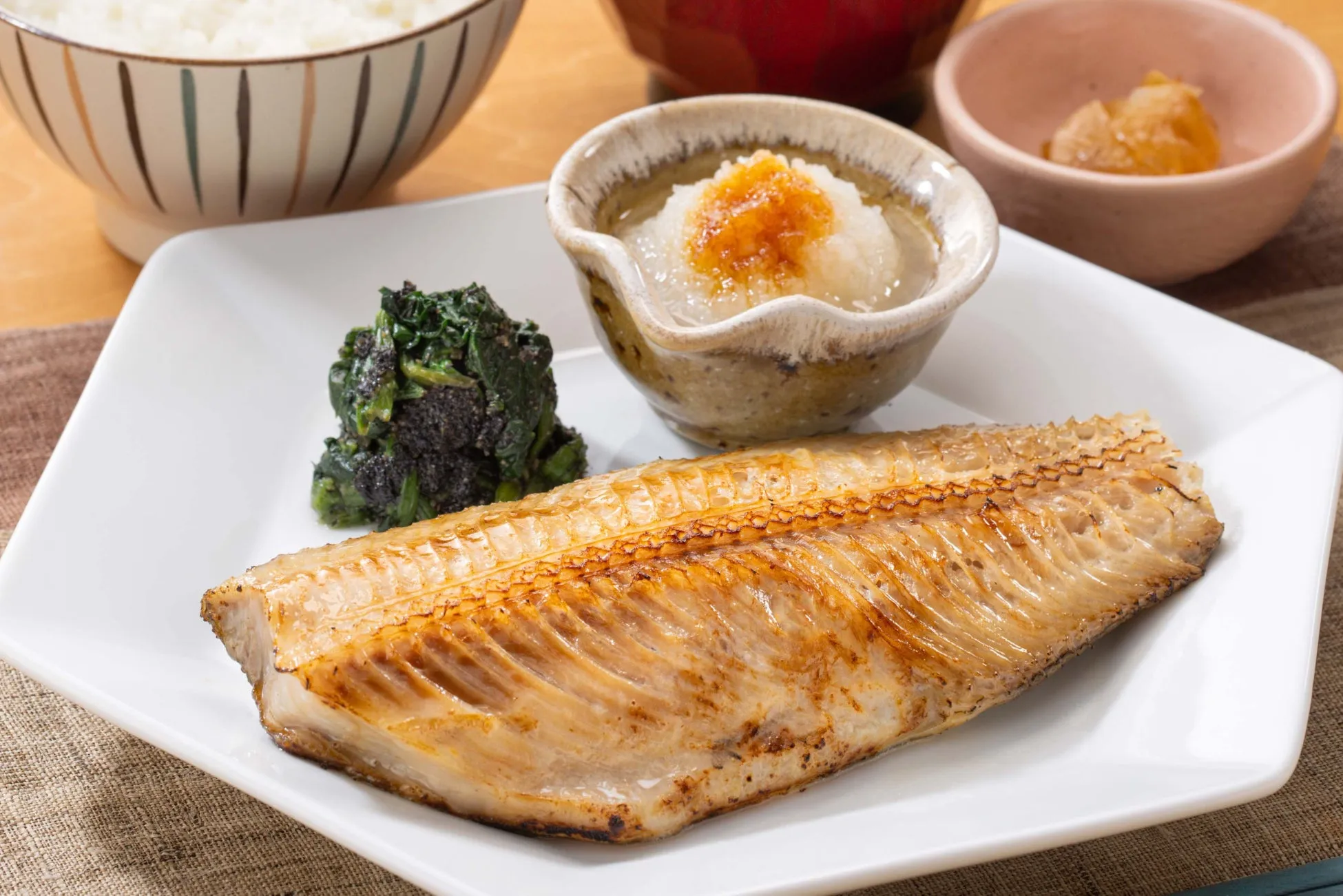 焼き魚の定食の写真です。焼き魚、ほうれん草のおひたし、大根おろし、ご飯などが写っています。