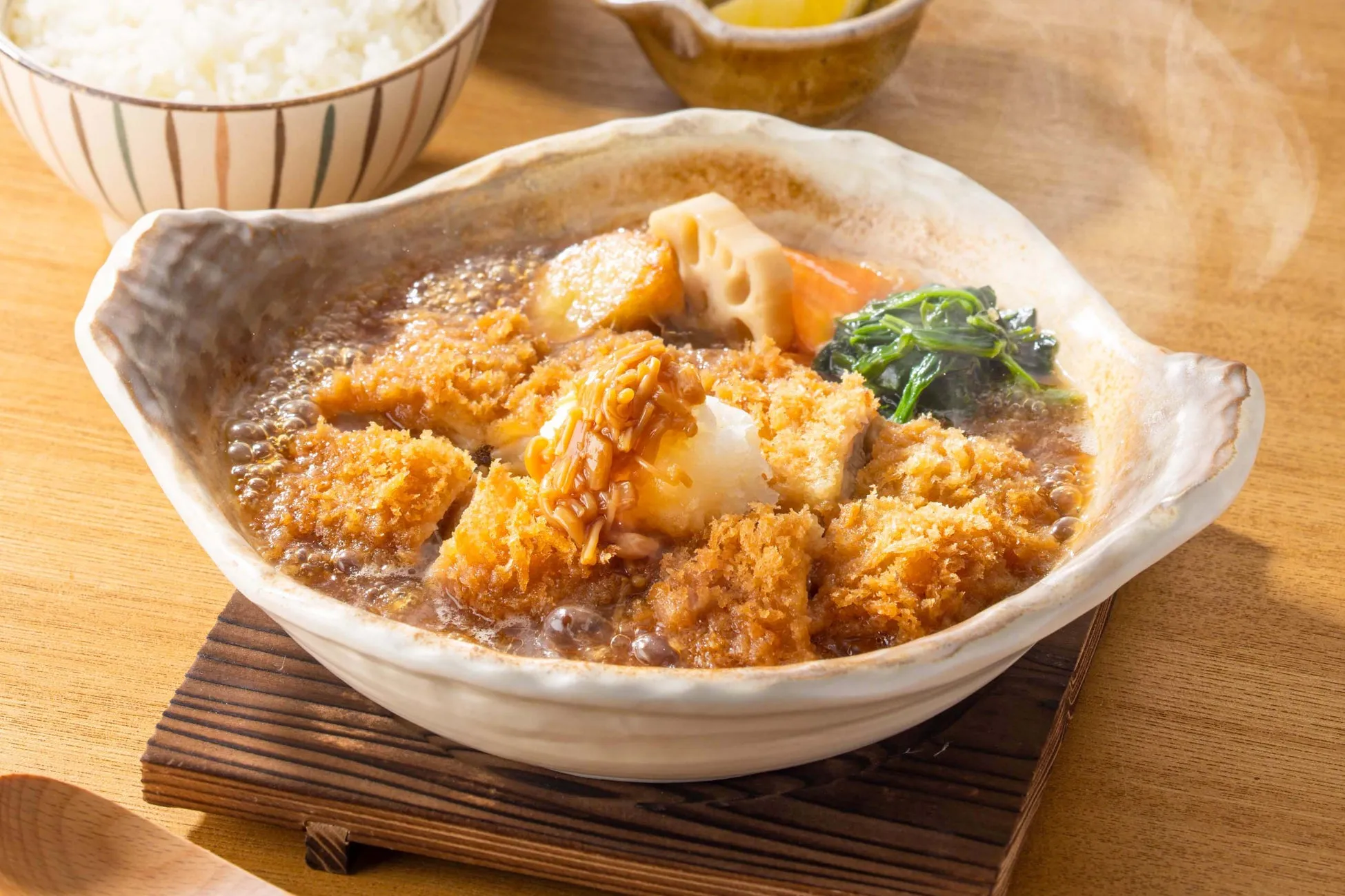 揚げられた豚肉と野菜が煮込まれた料理の画像。ご飯も写っている。
