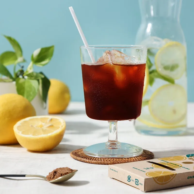 レモンとコーヒーが写った写真。グラスにはコーヒー、レモン水、レモン、コーヒーの粉末、そして箱が写っています。