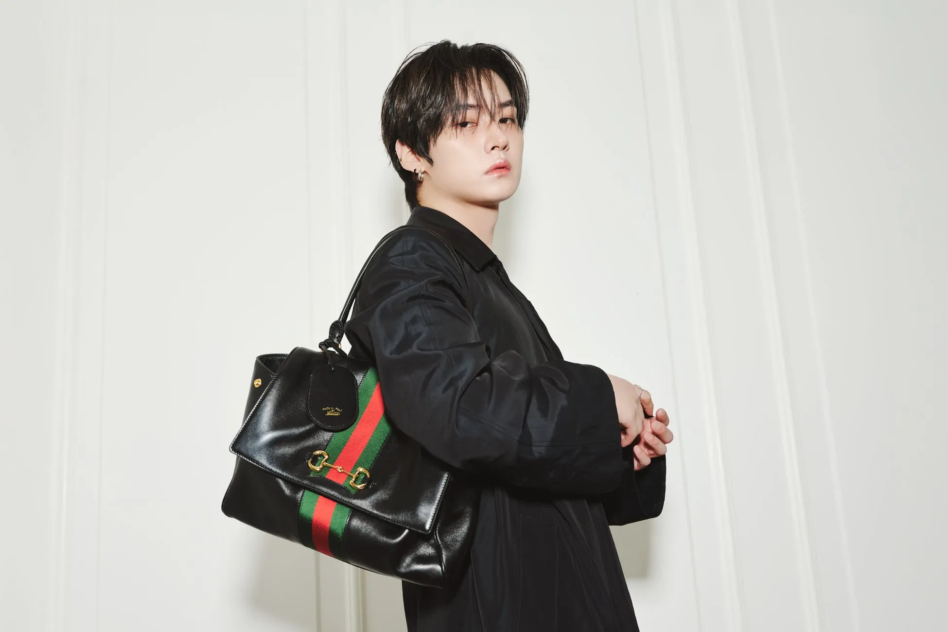 黒いジャケットを着てグッチのバッグを持った男性のポートレート