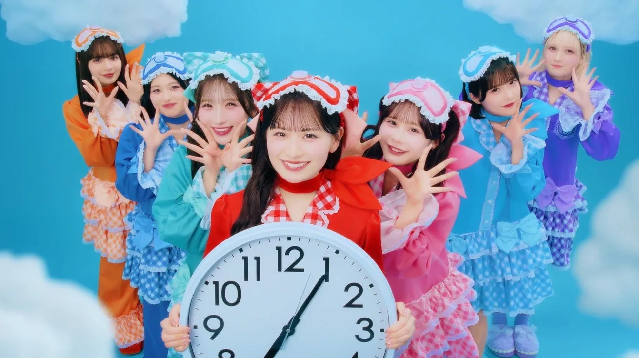 パジャマを着たアイドルグループの集合写真。メンバーは時計を持ち、笑顔でポーズをとっている。
