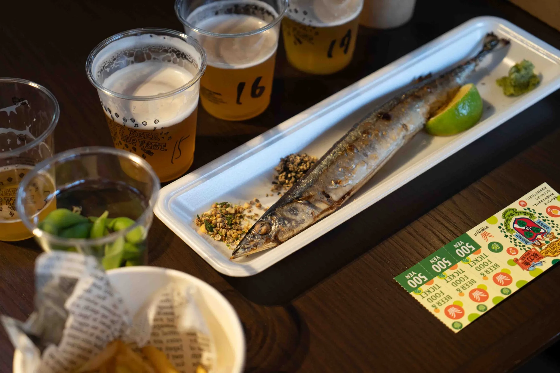 クラフトビールが注がれる様子と、グラス越しのグルメ