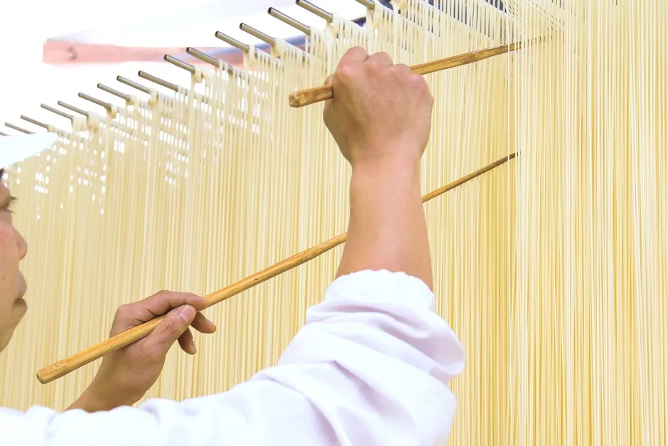 巽製粉の外観とロゴ、そして麺が写っています。