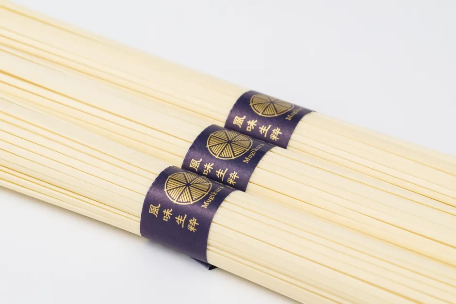 「むぎくらの麺」のパッケージと、湯気立つ麺のイメージ写真です。