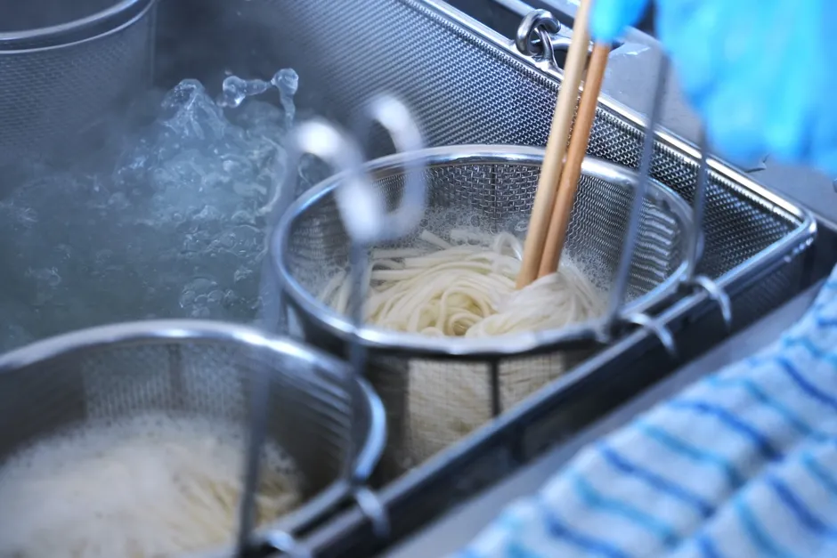 乾麺グランプリのブースで、来場者が麺を試食しています。