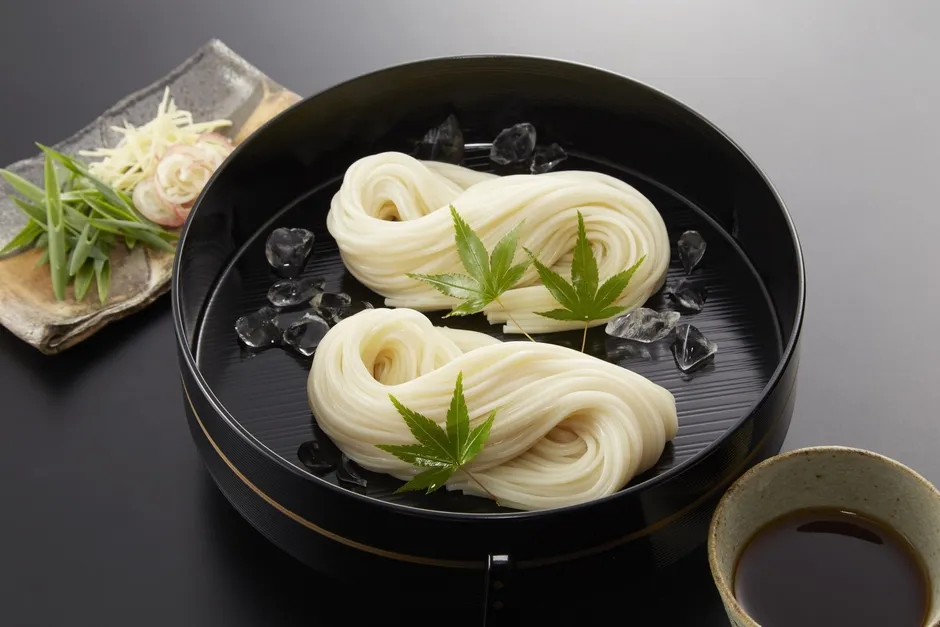手延べ麺の製造工程で、職人が麺を引き伸ばしている様子です。