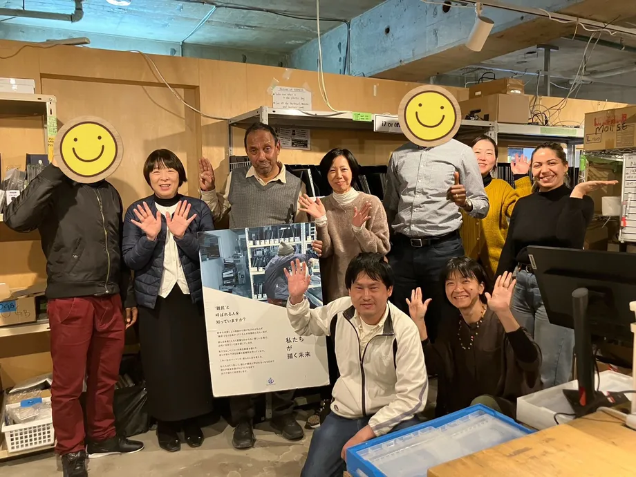 パソコンなどが並ぶ作業場で撮影されたピープルポートの集合写真
