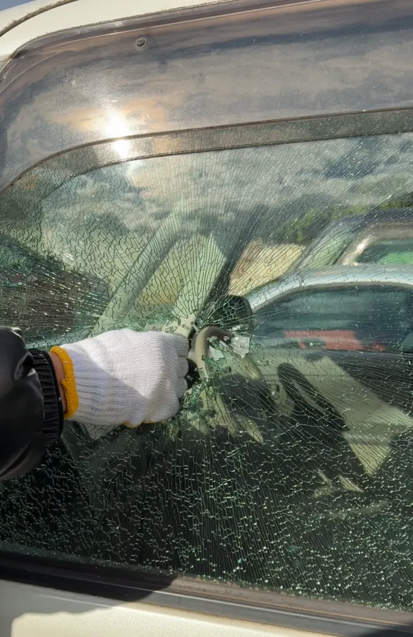 ひびが入った車の窓にハンマーを当てている提供写真