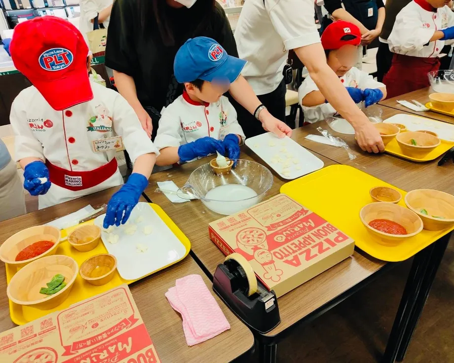 作業台でチーズ作りに取り組む子どもたちと大人