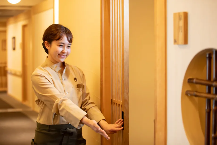 個室料亭の入口で案内するスタッフ