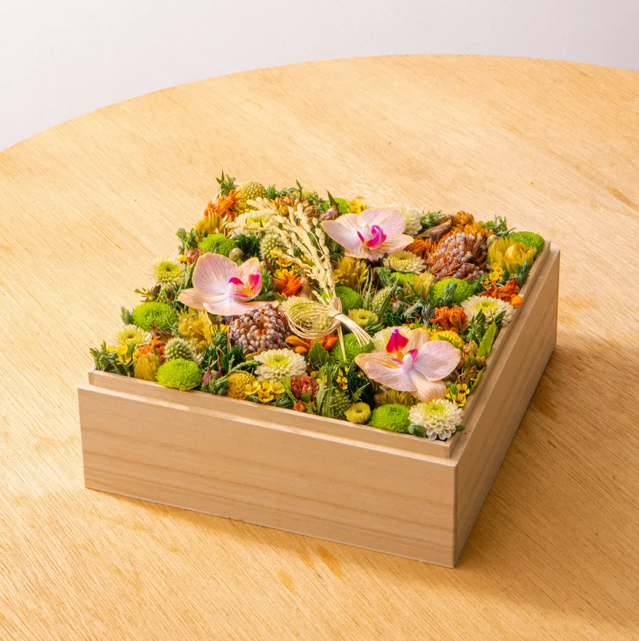淡い木箱に黄色やグリーンの花を合わせた作品