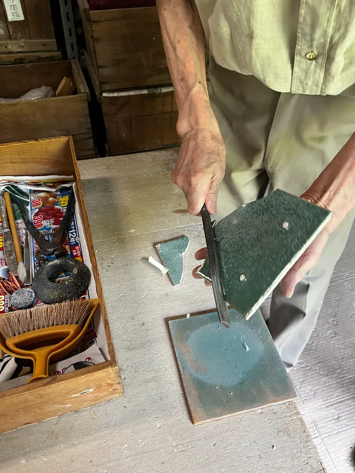 手に持ったタイルへ道具を当てる作業の手元
