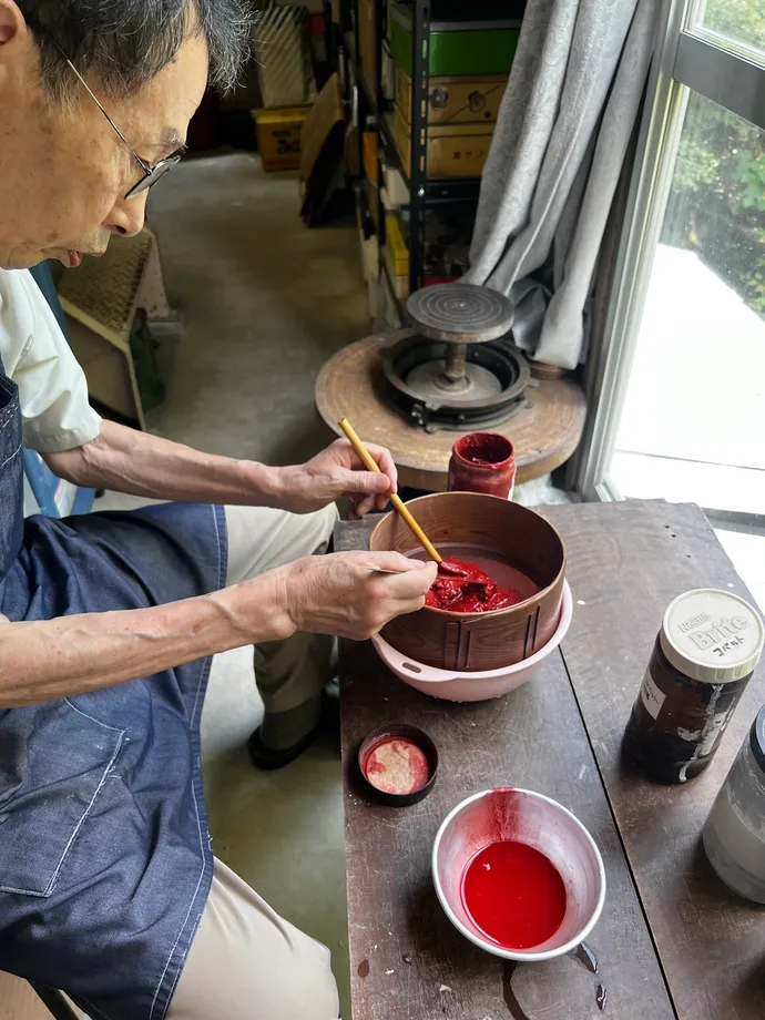 赤い釉薬を器の中で調合する作業