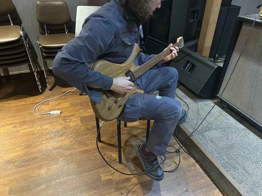 座ってI’mKのギターを弾く人と周囲の音響機材
