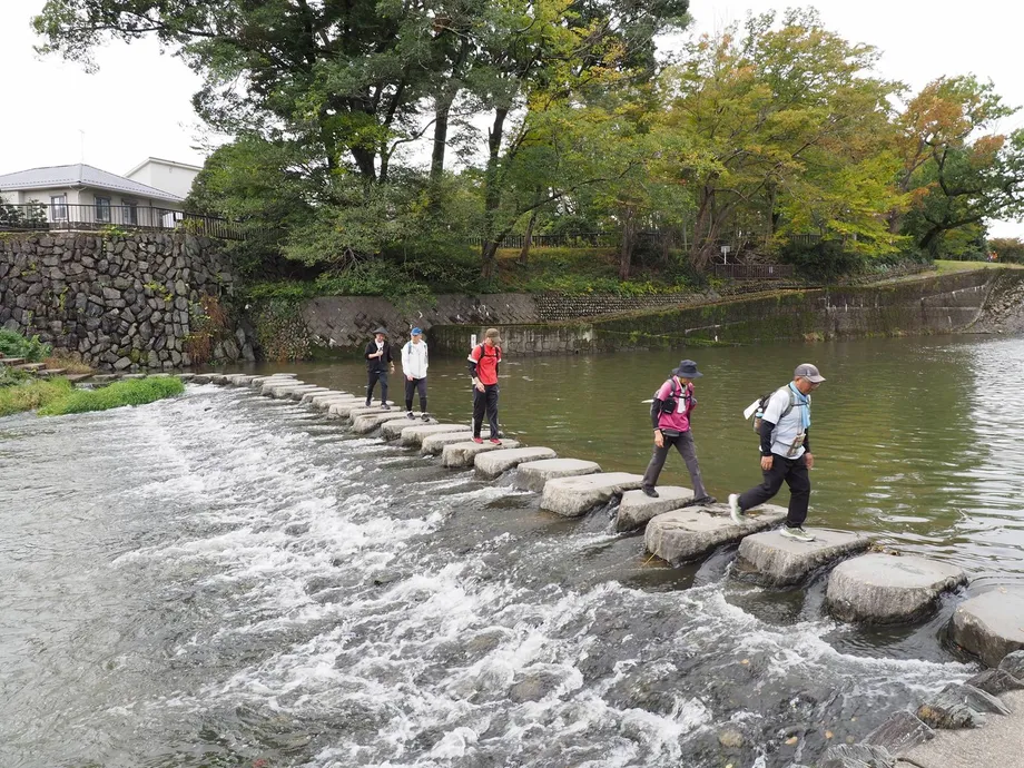 水辺の飛び石を渡る参加者