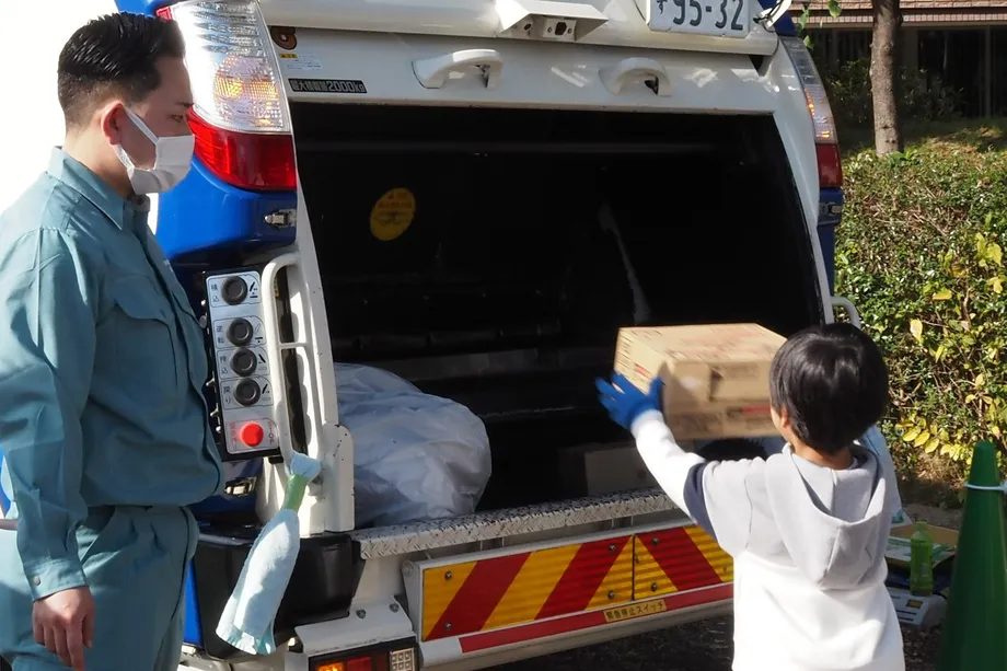 ごみ収集車に荷物を積み込む子ども