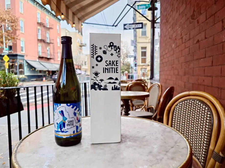 屋外のテーブルに置かれたSAKE INITIEの酒瓶と箱