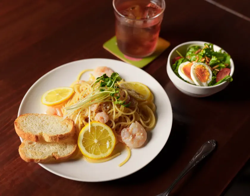 エビとレモンのパスタ、サラダ、飲み物がテーブルに置かれた料理の写真です。