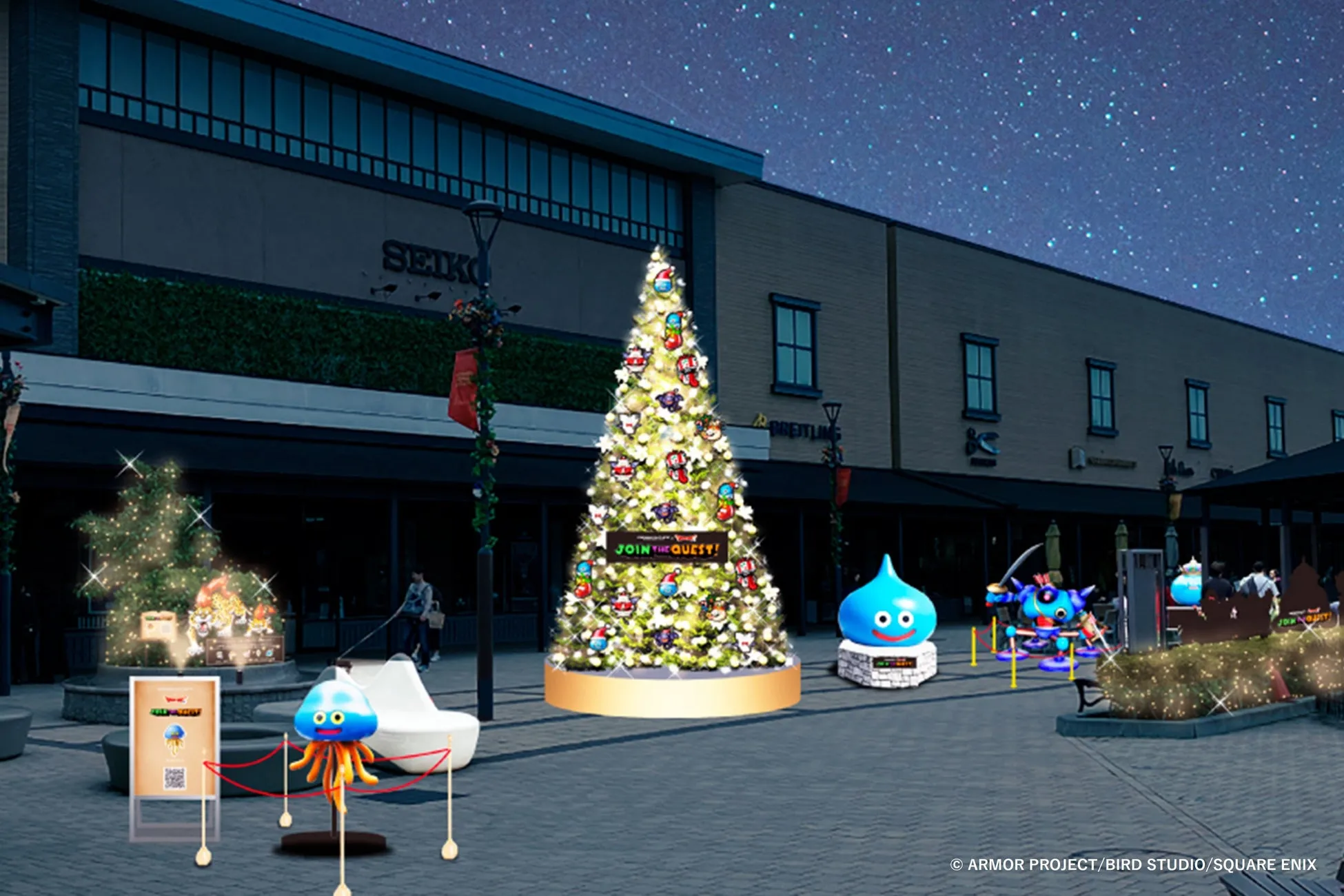 夜の街並みに設置された、クリスマスツリーとドラクエのスライムなどのキャラクターのイルミネーションの様子