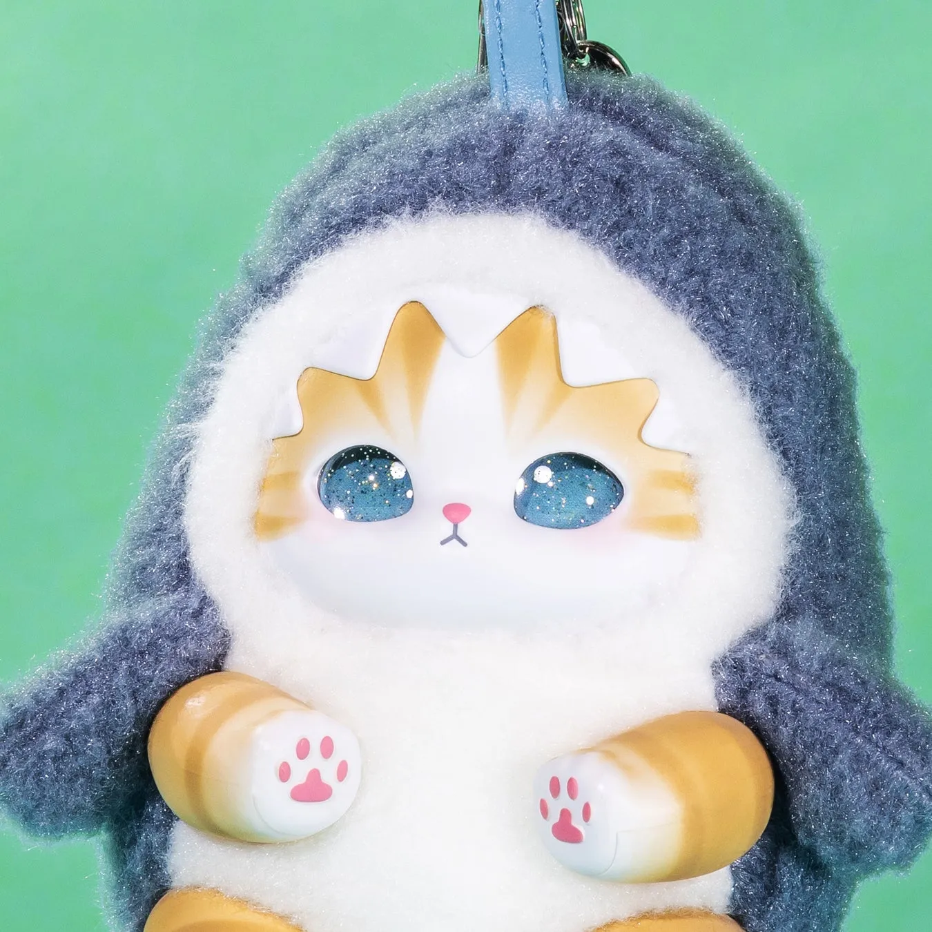 猫のぬいぐるみ。青いフワフワの着ぐるみを着ており、星空のような目とピンクの肉球が特徴的。