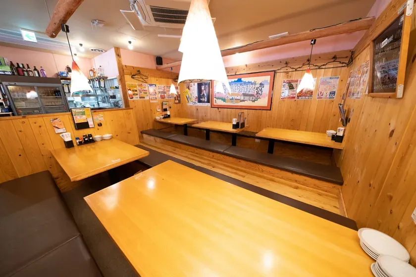 日本の居酒屋のインテリアの写真です。木製のテーブルとベンチ、日本の装飾品が特徴です。