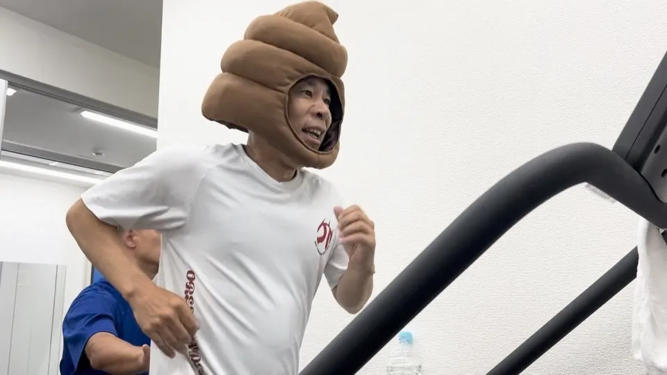 うんちの帽子をかぶった男性がトレッドミルで走っている様子