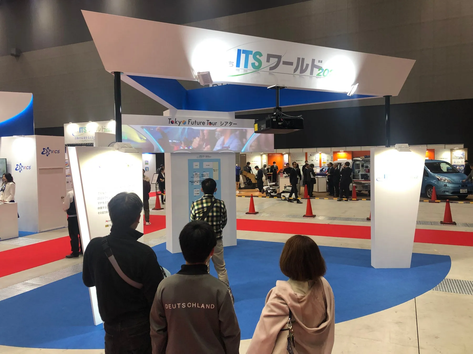 ITSワールド2023の展示会の様子。会場には多くの人が集まり、展示物を見学したり、説明を聞いたりしている。