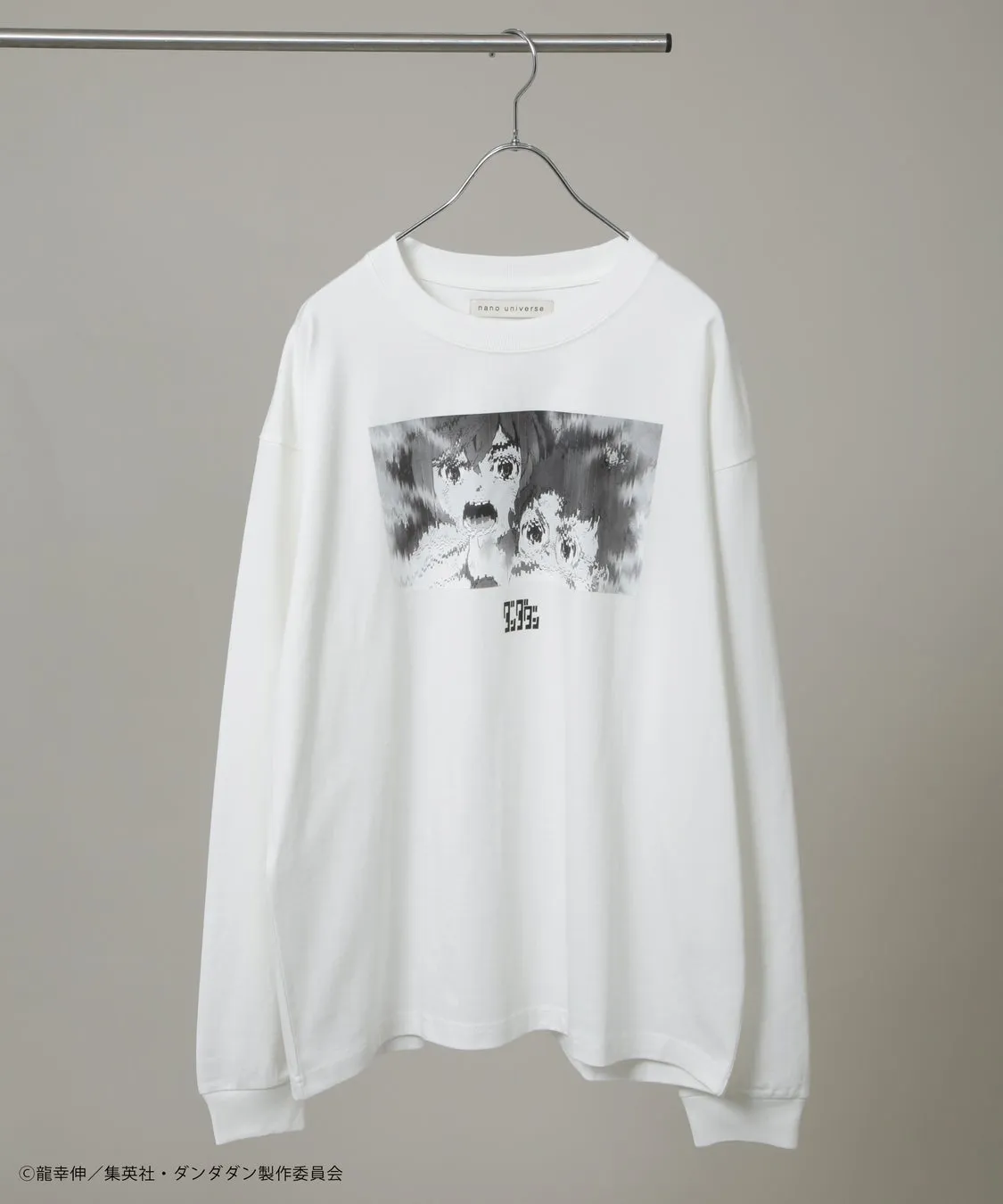 白い長袖Tシャツ。前面には、アニメのキャラクターのモノクロ画像がプリントされています。背景はグレーです。