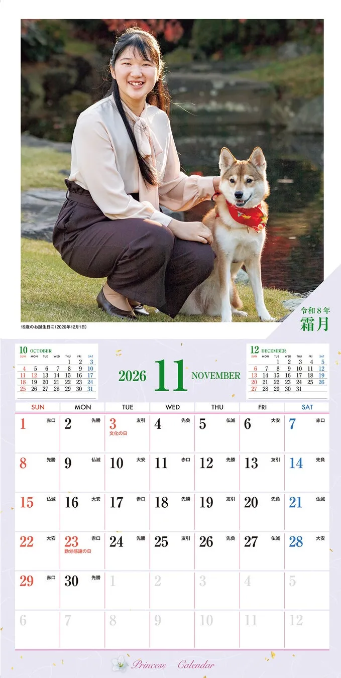 女性が犬を抱いて座っているカレンダーの画像。カレンダーには2026年11月と12月のカレンダーが表示されている。