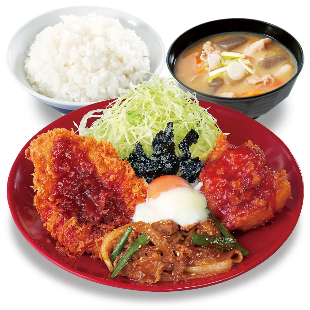 日本の定食の画像です。ご飯、味噌汁、揚げ物、サラダ、目玉焼き、肉料理が赤色の皿に盛り付けられています。