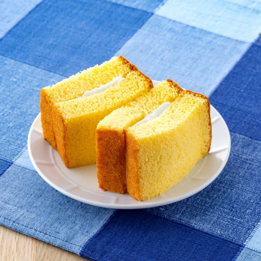 白いお皿に載った、クリームが挟まれたカステラのようなケーキのクローズアップ。