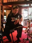 ギターを演奏する男性の画像。室内で、譜面台を見ながら演奏している様子。