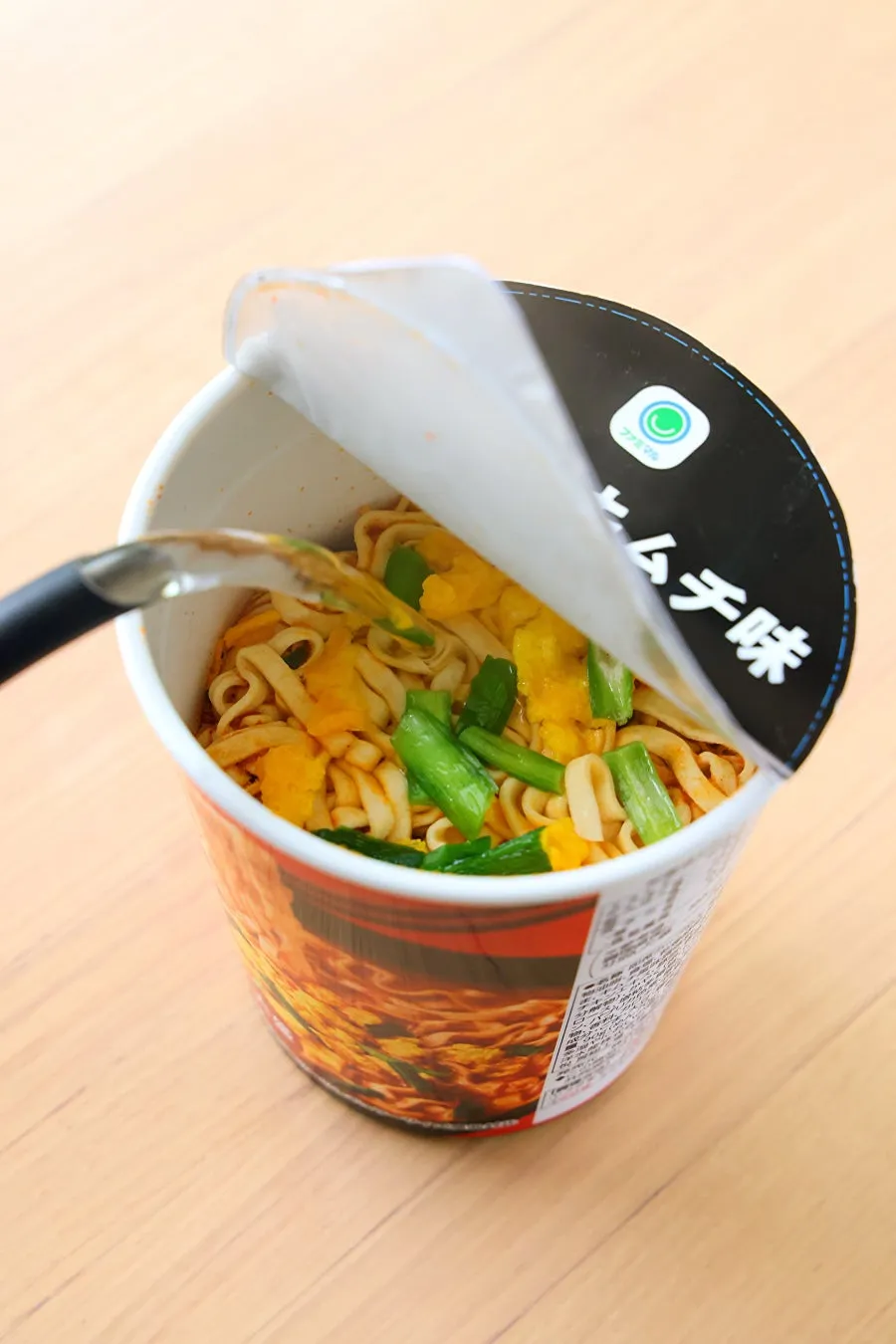 カップ麺にお湯を注いでいる様子を写した写真です。