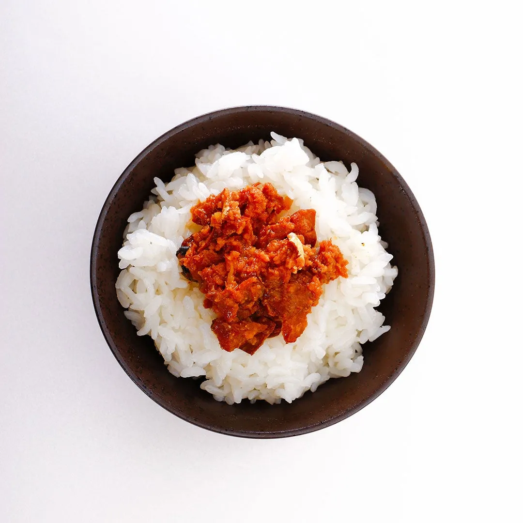 ご飯の上に、赤い色のソースが乗った料理の写真です。器は茶色で、背景は白です。
