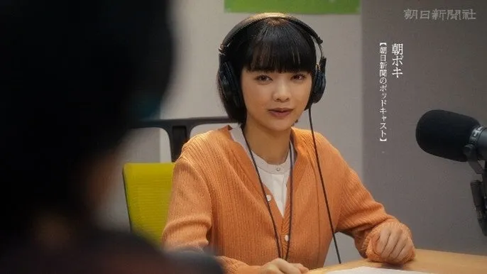 女性がヘッドホンをつけてマイクに向かい、ポッドキャストの収録をしている様子。