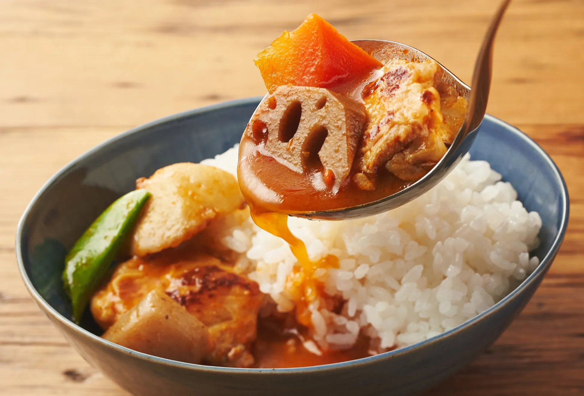 カレーライスをスプーンでご飯にかける様子