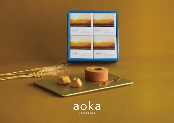 焼き菓子「aoka」のパッケージとバウムクーヘンが写った写真。夕焼けの風景が描かれたパッケージが印象的。