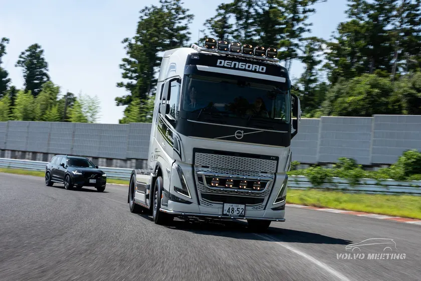 レーストラックを走行する白いボルボのトレーラーと黒いボルボ車。