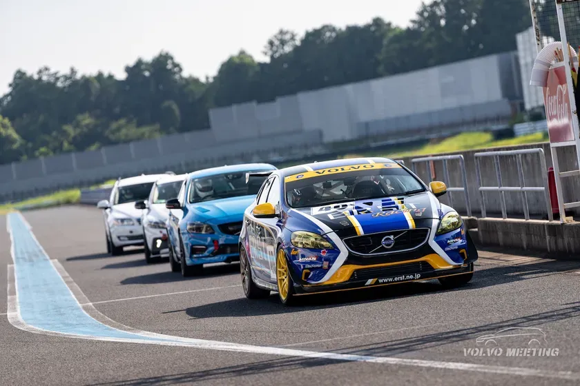 レーストラックに並んだボルボの車。正面に青と白のボルボがあり、その後に白いボルボと水色のボルボが続いている。