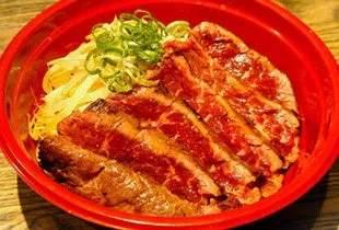牛肉が乗った丼。ネギと卵も添えられている。