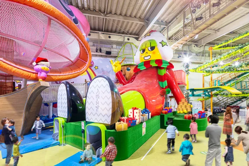 屋内遊園地の写真です。巨大なキャラクターが中央に配置され、子供たちが遊ぶ様子が写っています。クリスマスをテーマにした装飾が施されています。