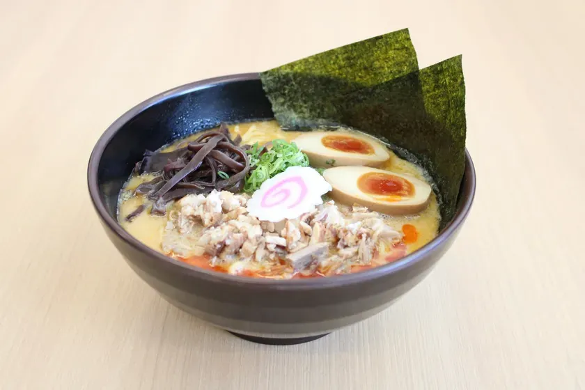 ラーメンのクローズアップ写真。ラーメンは、卵、海苔、ネギ、木耳、ナルトなどのトッピングが施されている。
